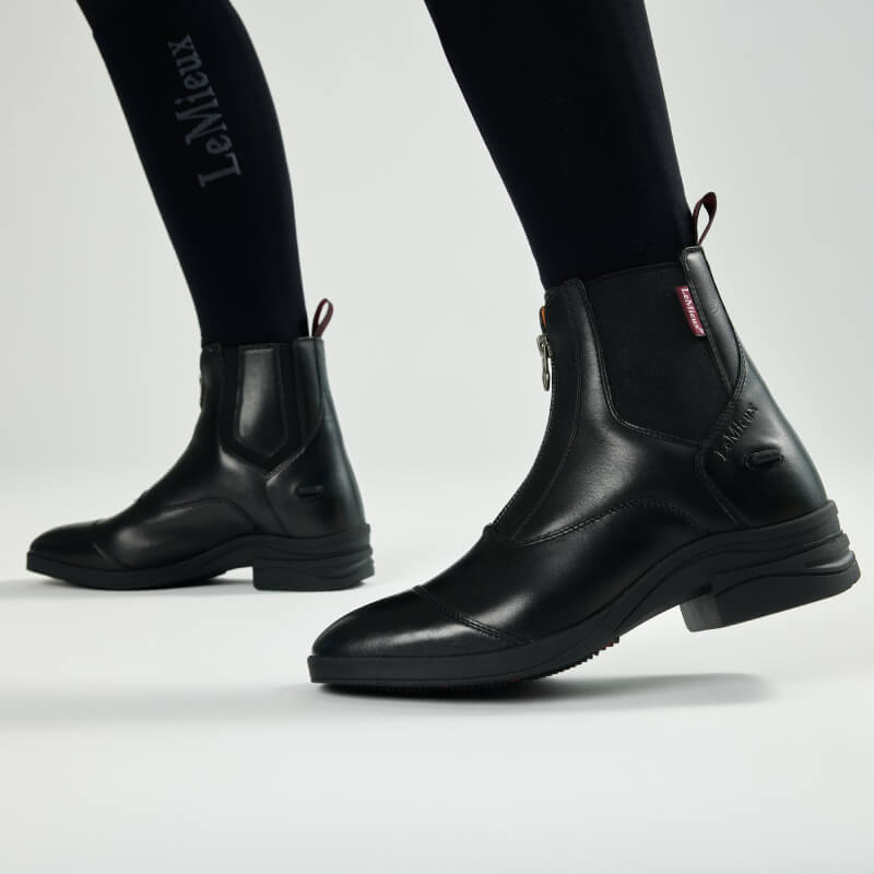 LeMieux Adults Zip Paddock Boot Black, worn with black leggings, shown walking side view.