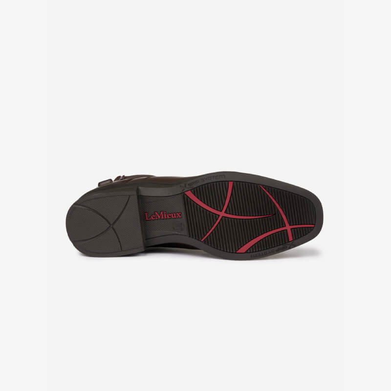 The sole of a LeMieux Adults Zip Paddock Boot Brown with black and red tread and logo is shown.