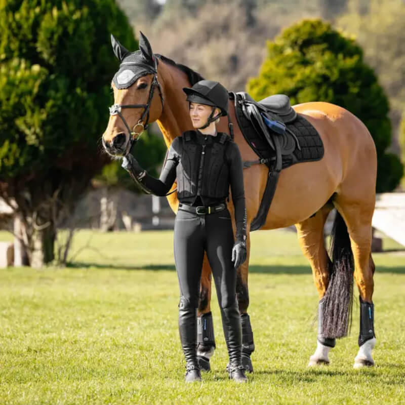 Rider stands by a saddled horse with a LeMieux 3D Mesh Self-Cool Eurojump Square Black.