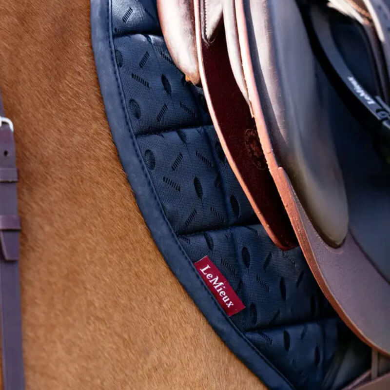 Close-up of a LeMieux 3D Mesh Self-Cool Eurojump Square Navy pad under a brown saddle.