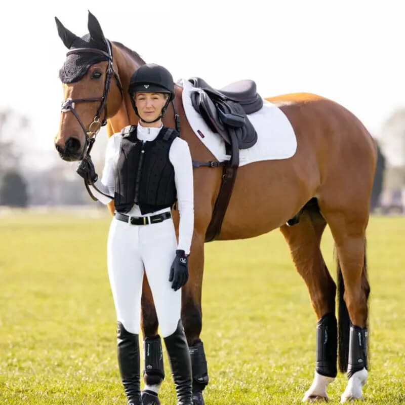 A rider stands by a horse with a LeMieux 3D Mesh Self-Cool Eurojump Square White saddle pad.