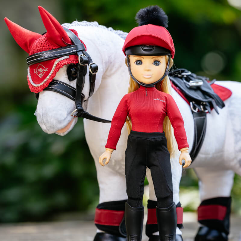 LeMieux Toy Rider Chloe stands next to a white toy horse with red and black accessories.