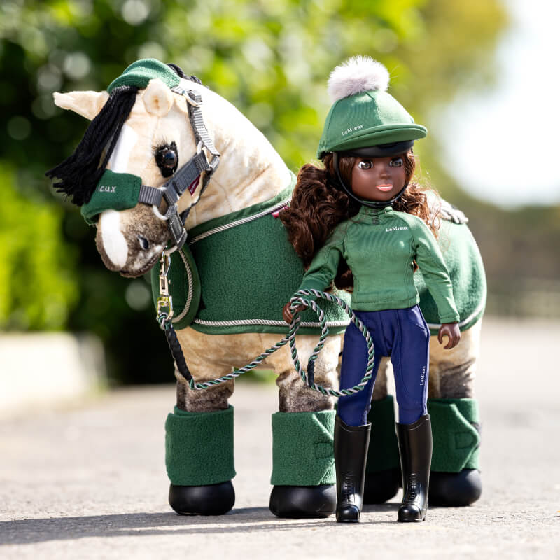 LeMieux Toy Rider Maya stands beside a plush horse, both wearing matching green LeMieux outfits.