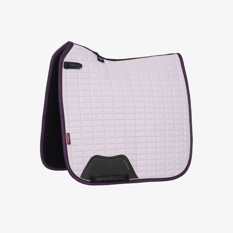 A black English saddle on a horse with a LeMieux lilac suede dressage square.