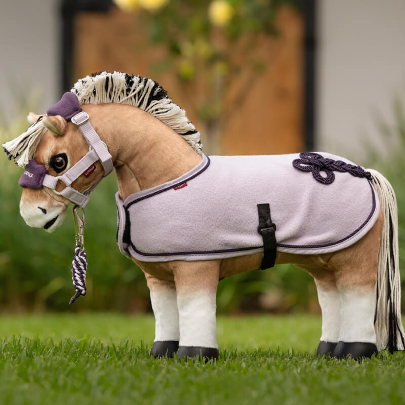 LeMieux Toy Pony Oskar stands on grass wearing a lavender blanket and bridle.
