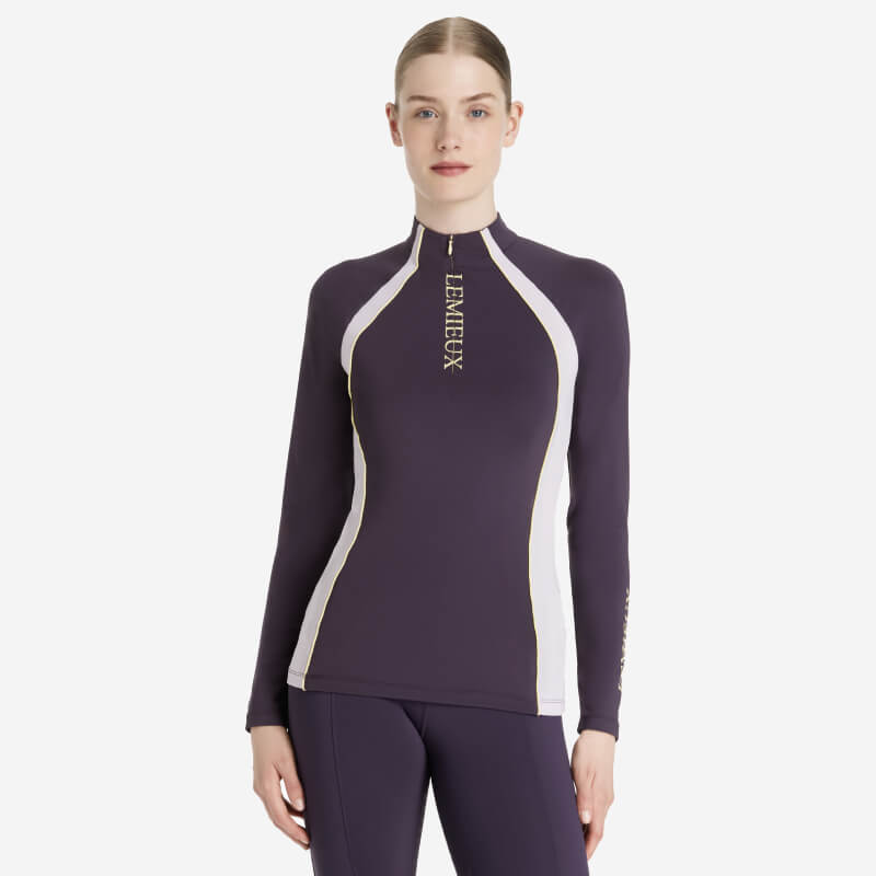 Woman wearing a fitted LeMieux Phillipa Mesh Baselayer in Juniper with LEMIEUX on the front.