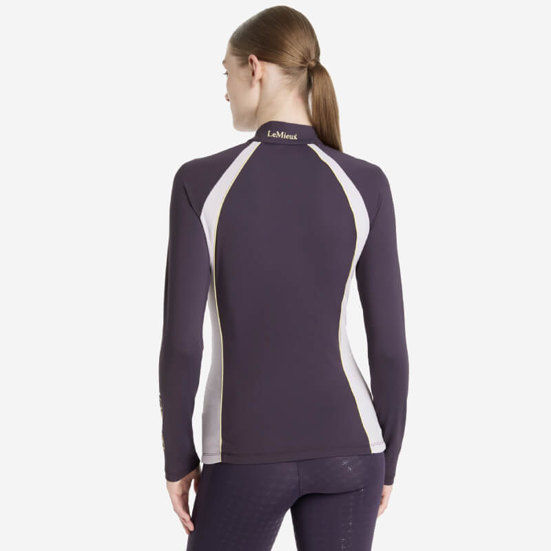 Woman with long hair wears LeMieux Phillipa Mesh Baselayer Juniper, viewed from the back.