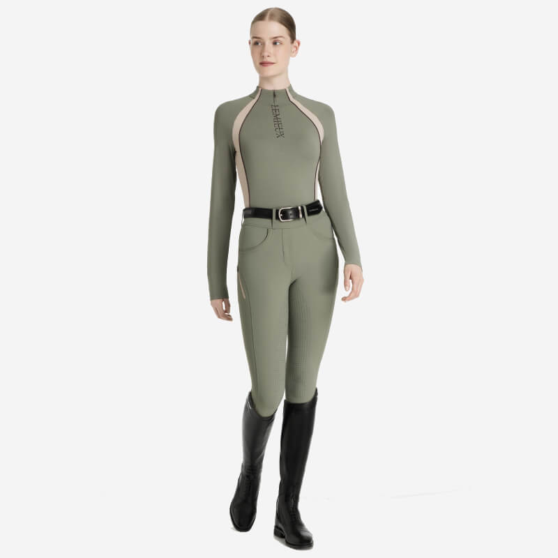 Woman in a LeMieux Phillipa Mesh Baselayer Rosemary, black boots, and a black belt.