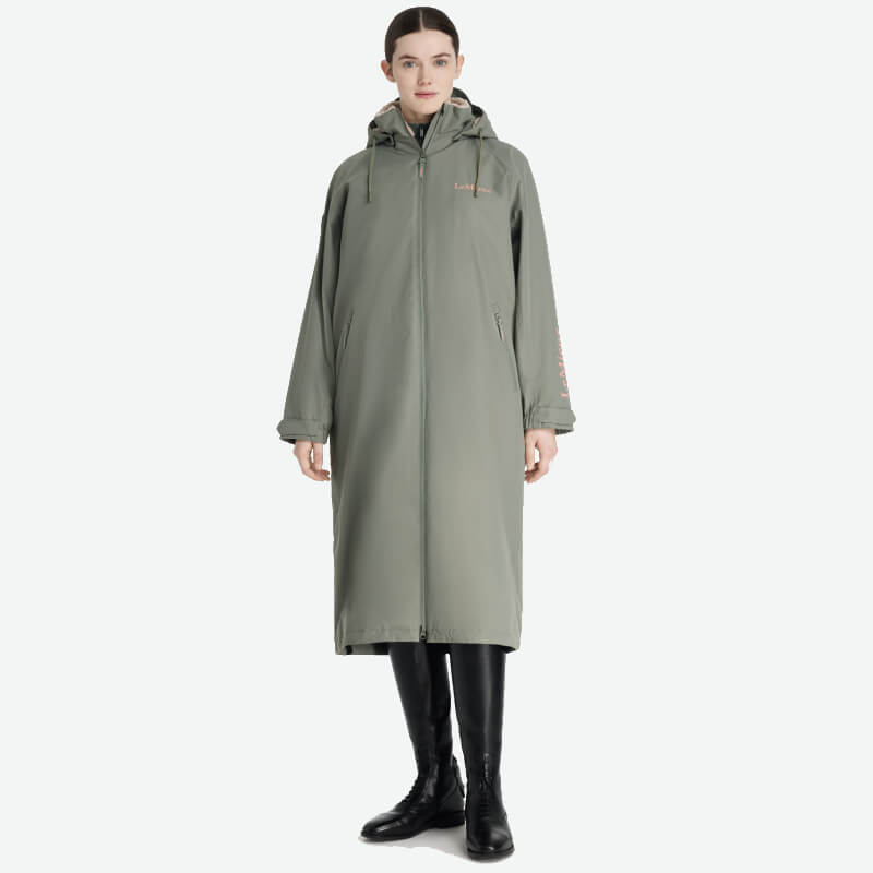 Woman in a LeMieux Hydroshield Robe Rosemary, olive green, with black boots, facing forward.