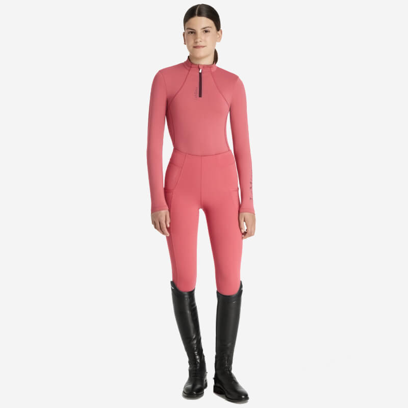 Girl in a LeMieux Young Rider Classique Baselayer Cranberry and black knee-high boots, smiling.
