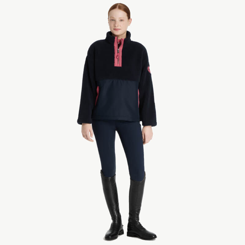 Woman in LeMieux Young Rider Tammy Teddy Fleece Navy and leggings, with black boots.