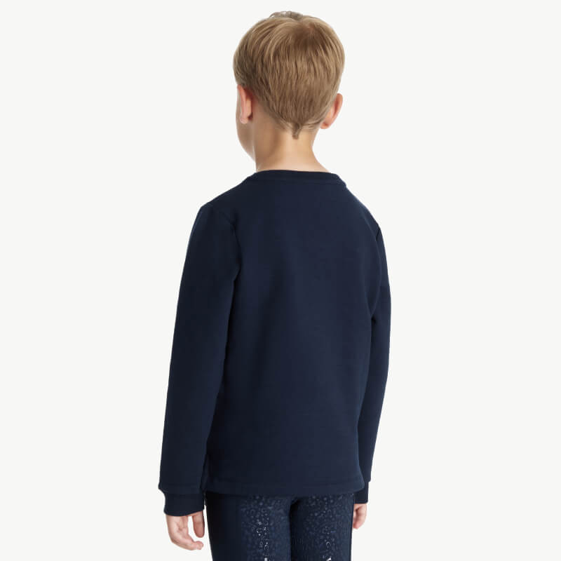 Young boy with light brown hair wears LeMieux Mini Poppy Long Sleeve Top Navy, seen from behind.