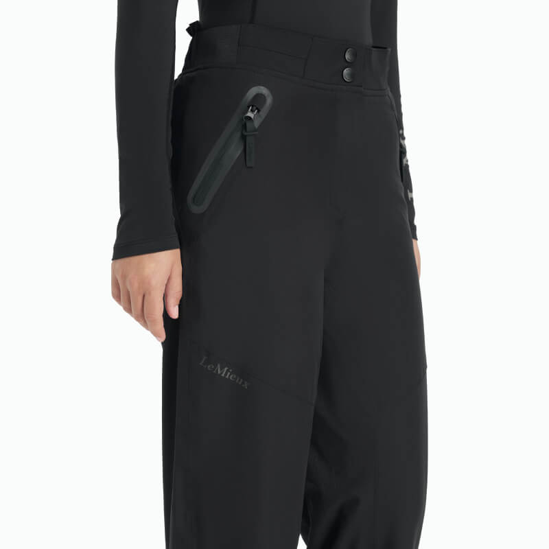 Person wearing LeMieux Young Rider Drytex Stormwear Waterproof Trousers Black and a black top.