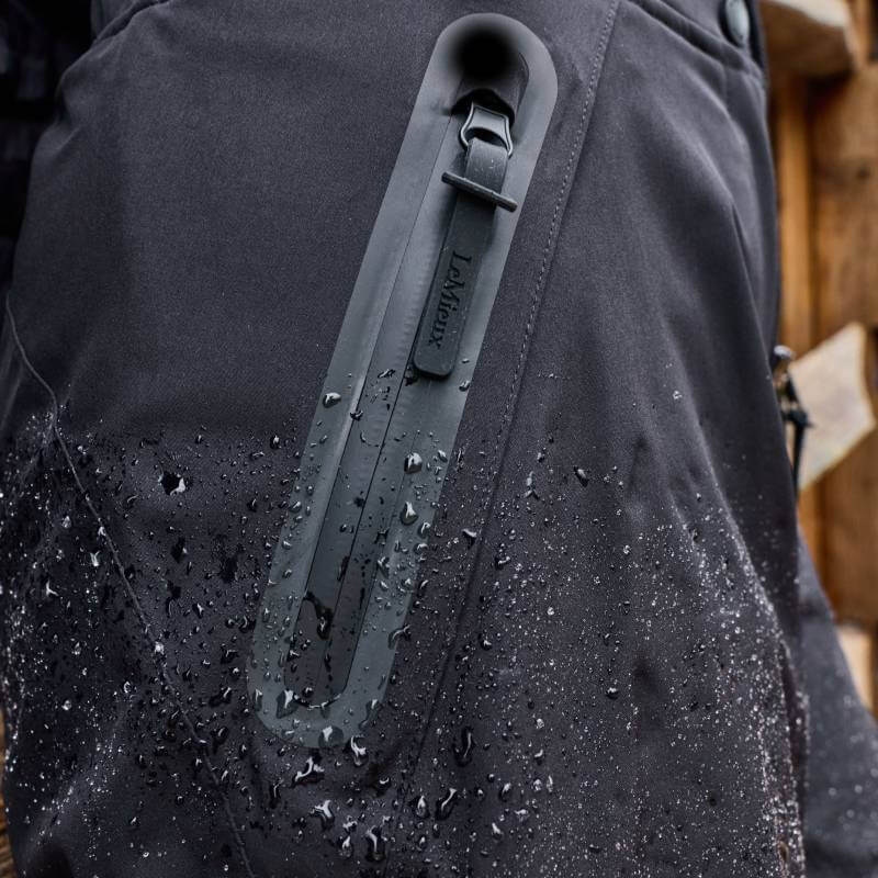 Close-up of LeMieux Stormwear Waterproof Trousers Black with water droplets and zippered pocket.