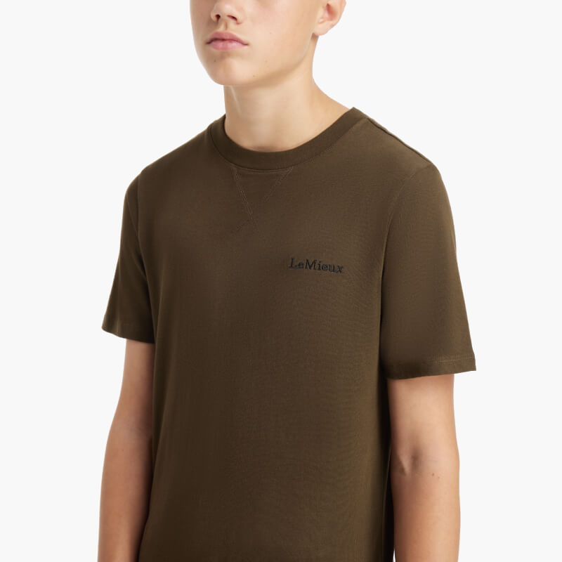 Teen boy in a LeMieux Young Rider Boys T-Shirt Alpine and black pants on a white background.