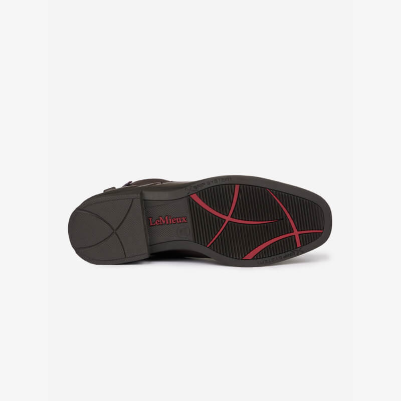 The sole of a LeMieux Junior Zip Paddock Boot Brown with red accents and LeMieux logo underneath.
