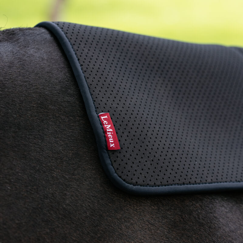 LeMieux Non-Slip Half Pad Square Black draped on a fence for horse comfort outdoors.
