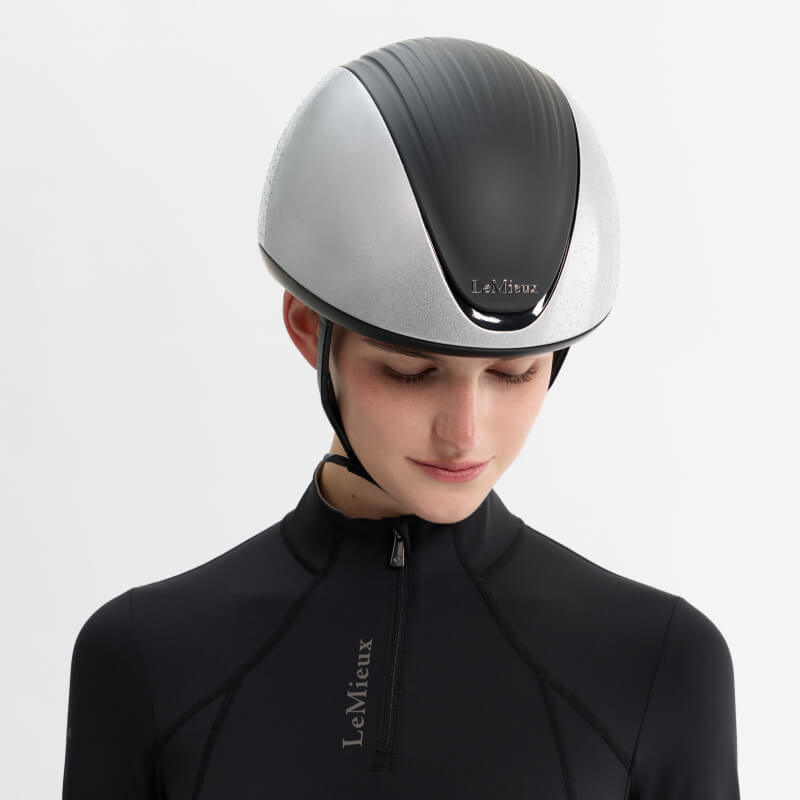 Person wearing a LeMieux Vexa® Skull Helmet Silver and a black zip-up top.