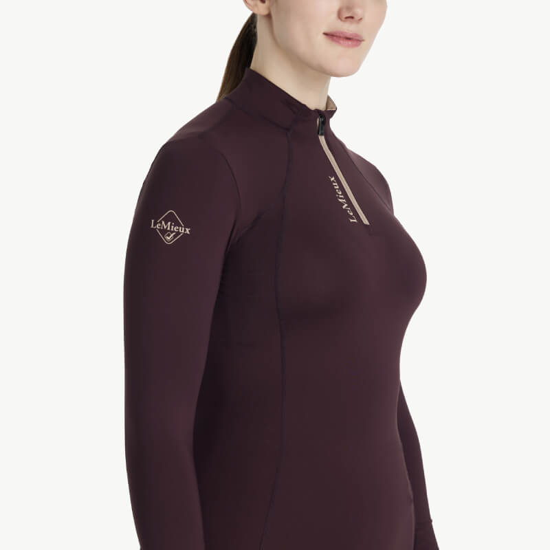 Woman wears LeMieux Classique Baselayer Damson with LeMieux branding on the sleeve.