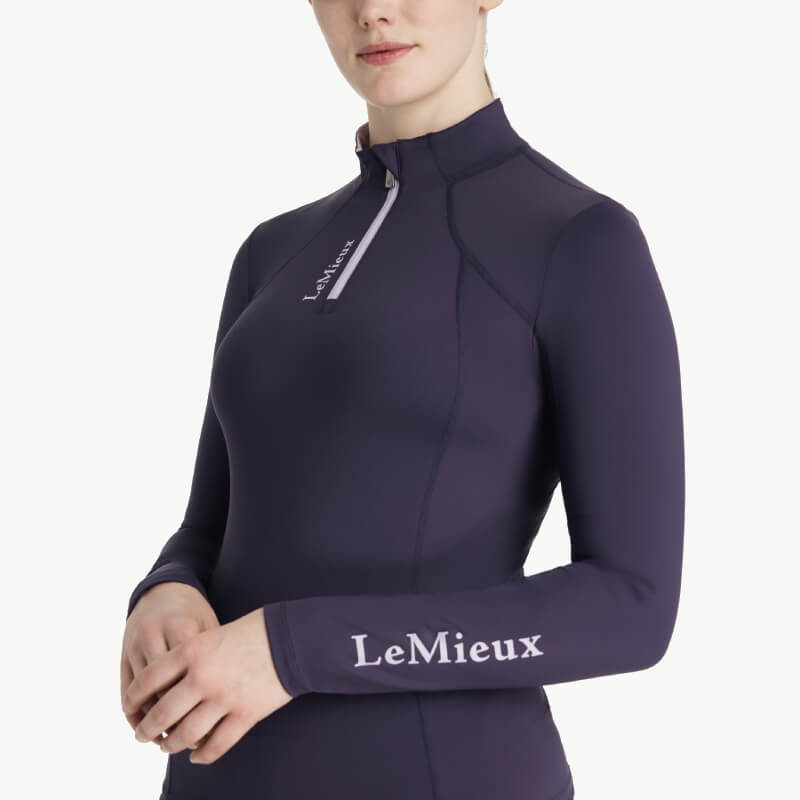 Woman in a fitted LeMieux Classique Baselayer Juniper, standing facing forward.