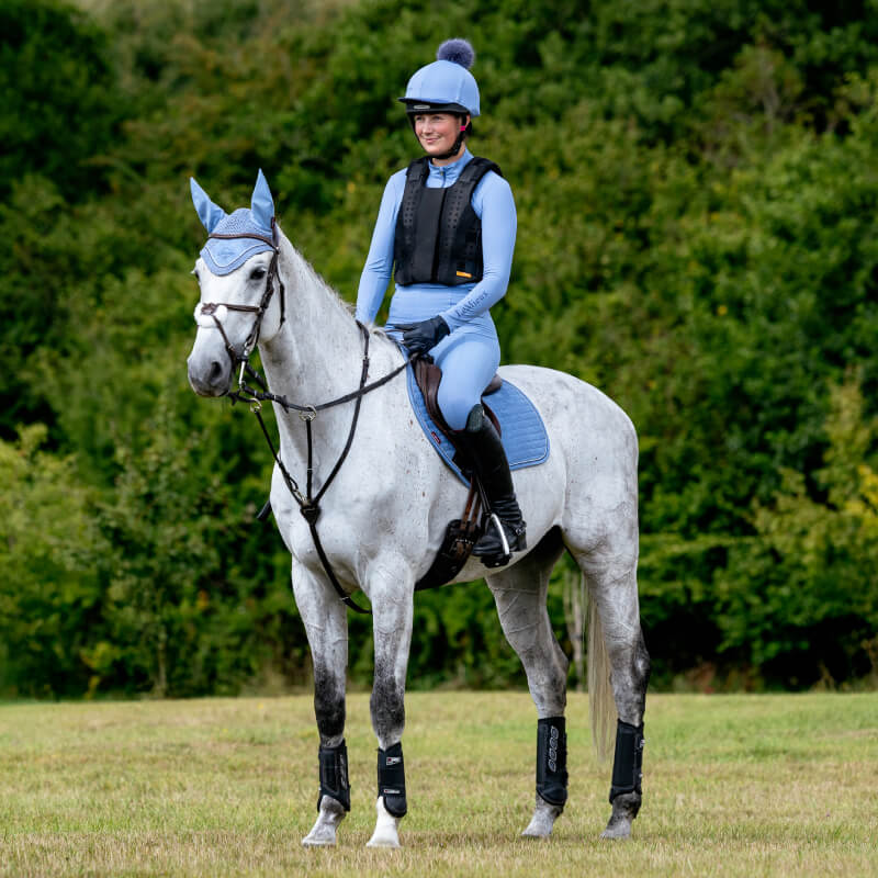 Rider in blue on a gray horse with LeMieux Suede Close Contact Square Powder Blue saddle pad.