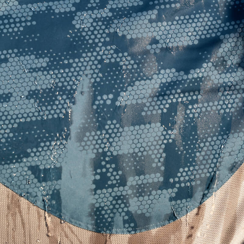 Water beads on a LeMieux Arika Camo Shower-Tek Fly Rug Jungle with blue and tan trim.