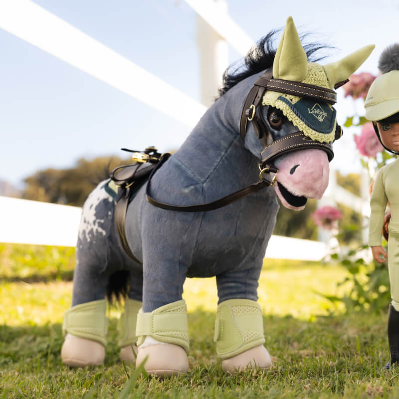 LeMieux Toy Pony Comet with plaitable mane and tail stands on grass near a riding doll.