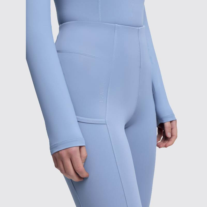 Model wears LeMieux Naomi Pull On Breech in Powder Blue, featuring long sleeves and high waist.