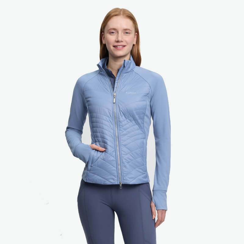 Woman in a LeMieux Juliette Jacket Powder Blue, standing and smiling.