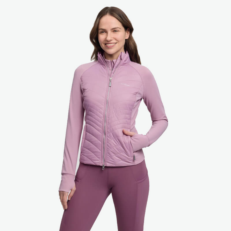 Woman in LeMieux Juliette Jacket Fondant by LeMieux, standing and smiling.