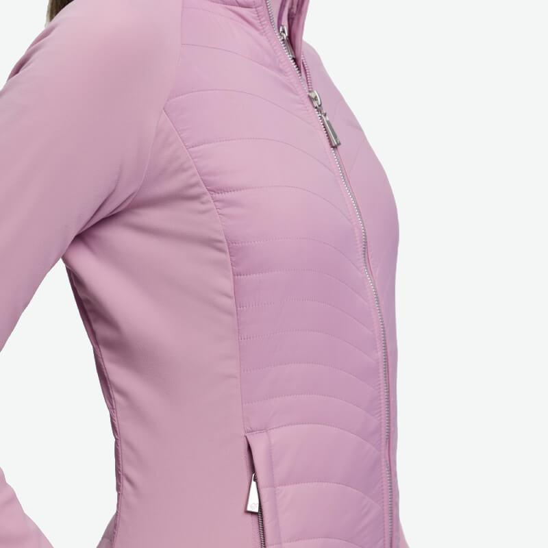 Person wearing a LeMieux Juliette Jacket Fondant, a light pink quilted jacket, shoulder to hip.