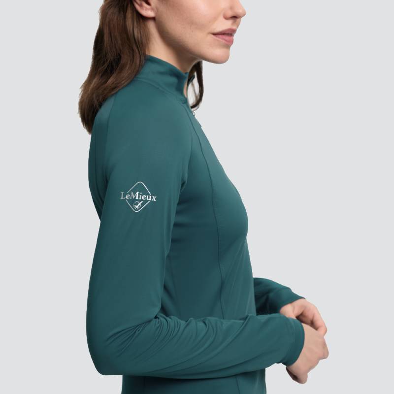 Woman in LeMieux Halle Lightweight Base Layer Jungle, logo on sleeve, facing sideways.