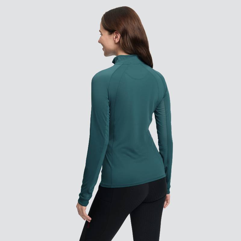 Smiling woman in LeMieux Halle Jungle base layer, facing away, paired with black pants.