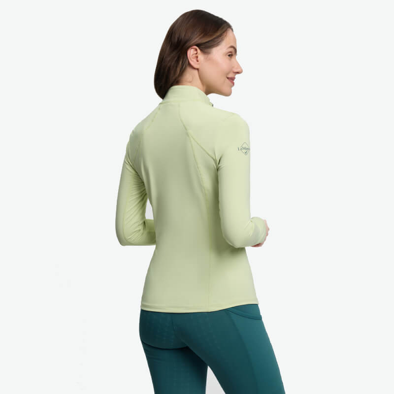 Woman in a LeMieux Classique Baselayer Macaron and green leggings, seen from the back.
