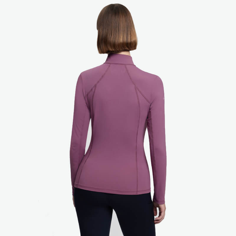 Woman with short brown hair wears a fitted LeMieux Classique Baselayer Mallow, seen from the back.