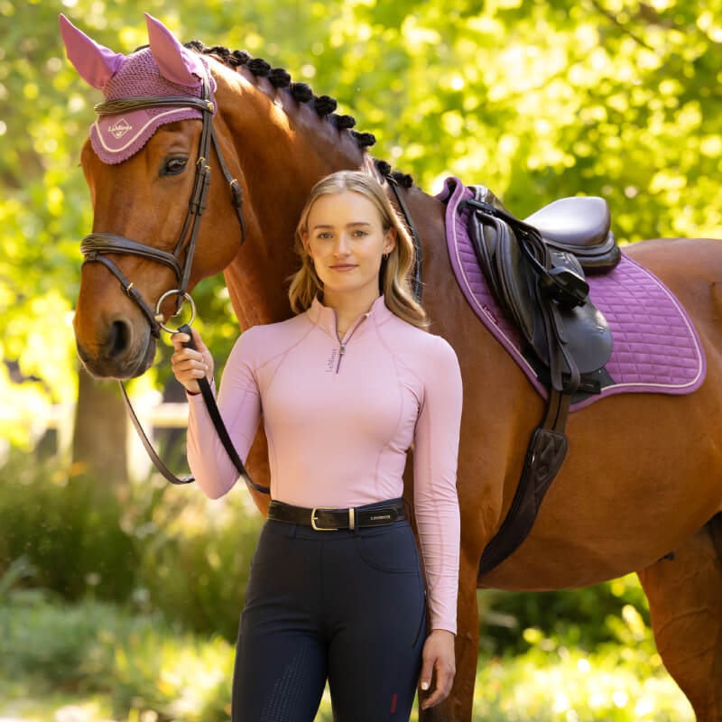 Woman smiles confidently in a LeMieux Classique Baselayer Fondant, arms crossed.