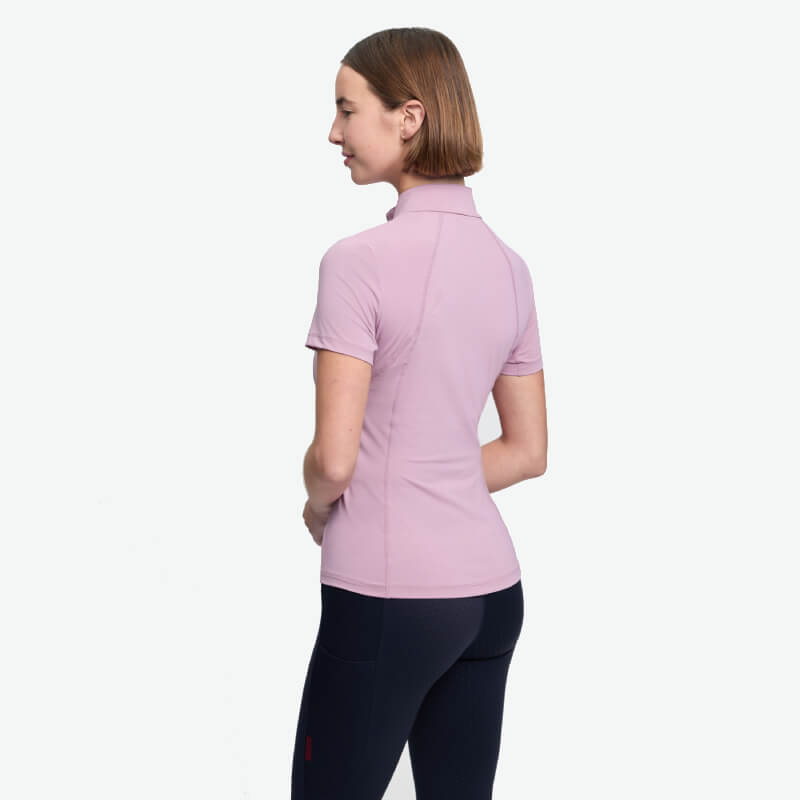 Woman in a LeMieux Classique Short Sleeve Baselayer Fondant, black leggings, back to camera.