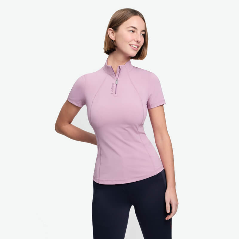 Smiling woman in LeMieux Classique Fondant baselayer, black pants, hand behind back.