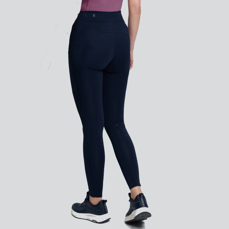 Person in LeMieux Simone Cross Over Half Seat Pull On Navy and sneakers, back view, on gray.