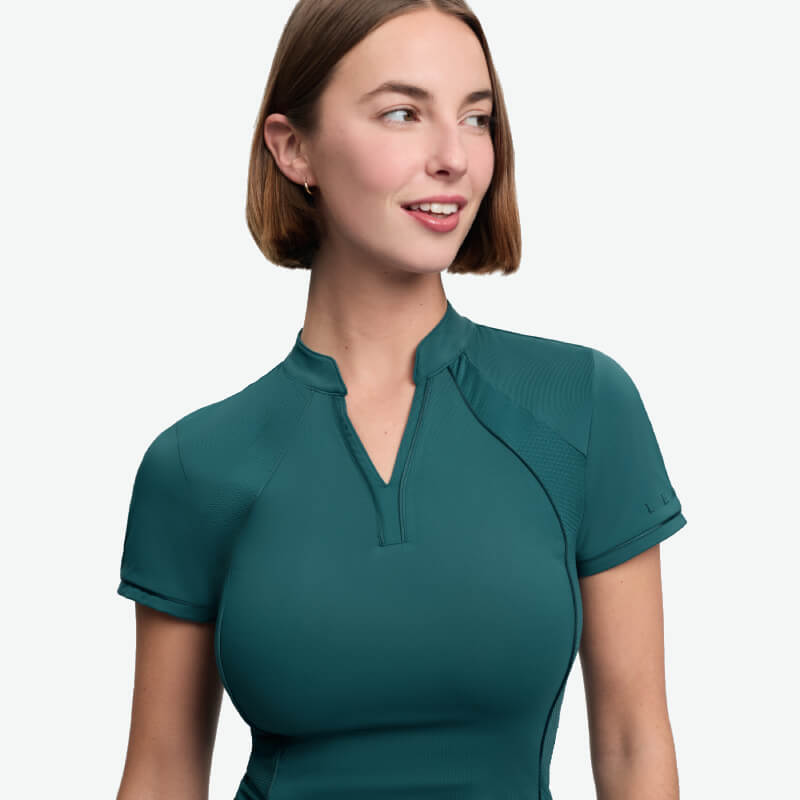 Woman in a LeMieux Lisa Mesh Baselayer Jungle smiles, looking left against a white background.