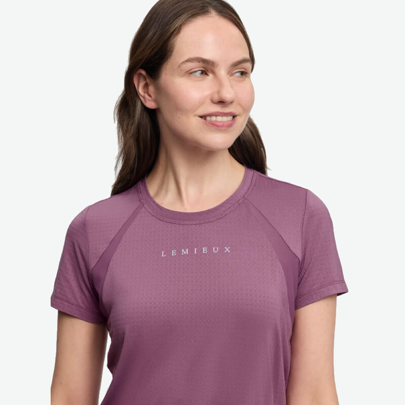 Woman in LeMieux Sports T-Shirt Mallow smiles, looking aside against a white background.