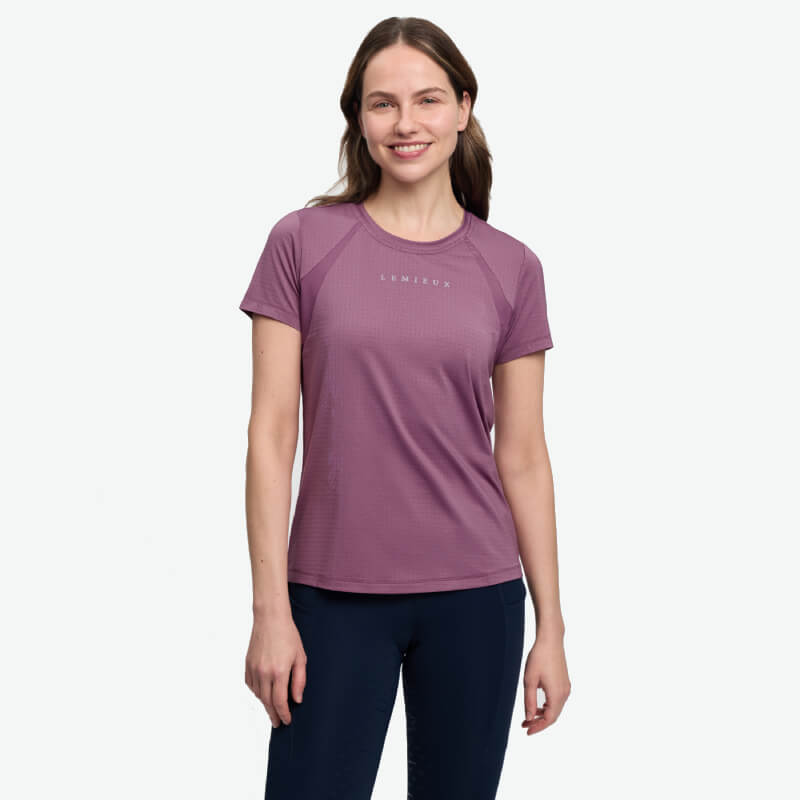 Woman in a LeMieux Sports T-Shirt Mallow and navy pants smiles at the camera.