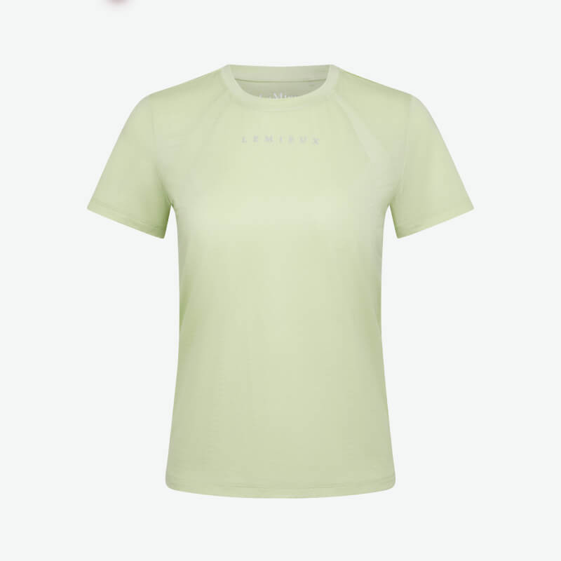 Woman in a LeMieux Sports T-Shirt Macaron and black pants smiling against a white background.