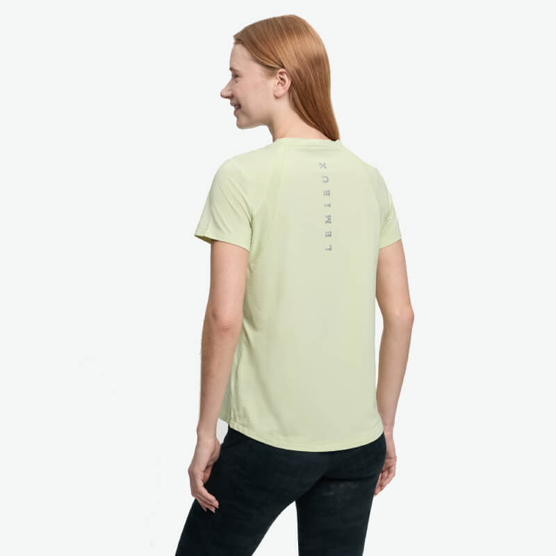 Woman in a light green LeMieux Sports T-Shirt Macaron, “LEMIEUX” on the back, faces away.