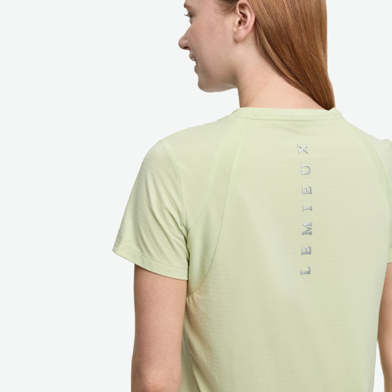 Woman in LeMieux Sports T-Shirt Macaron, light green, LEMIEUX printed vertically on back.