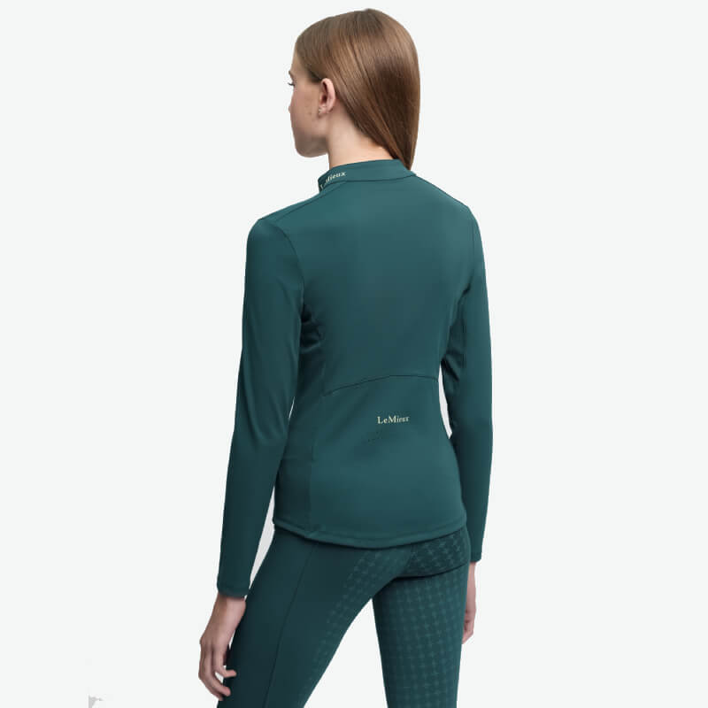 Smiling teen in a LeMieux Young Rider Airflow Baselayer Jungle, teal long-sleeve riding shirt.