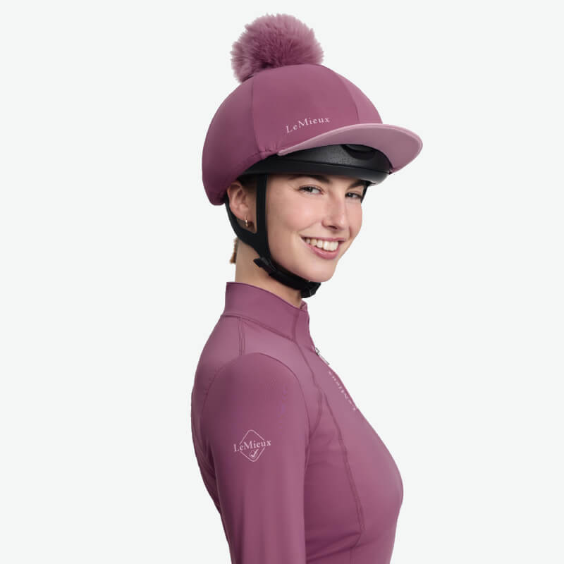 LeMieux Classique Pom Hat Silk Mallow: pink riding hat cover with pom and black strap.