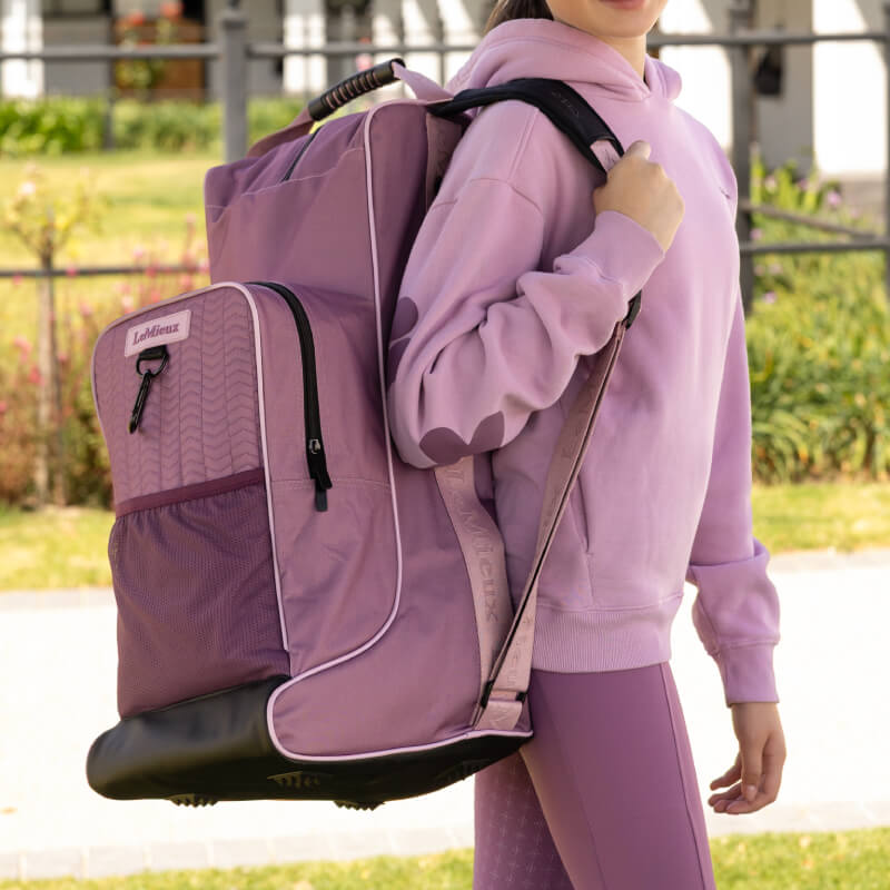 Person in pink with LeMieux Boot & Hat Bag Mallow by LeMieux outdoors on a sunny day.