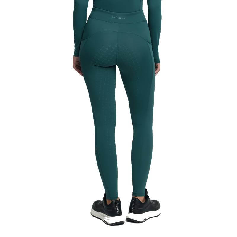 Person in teal leggings and sneakers, back view, wears LeMieux Young Rider Orla Breech Jungle.