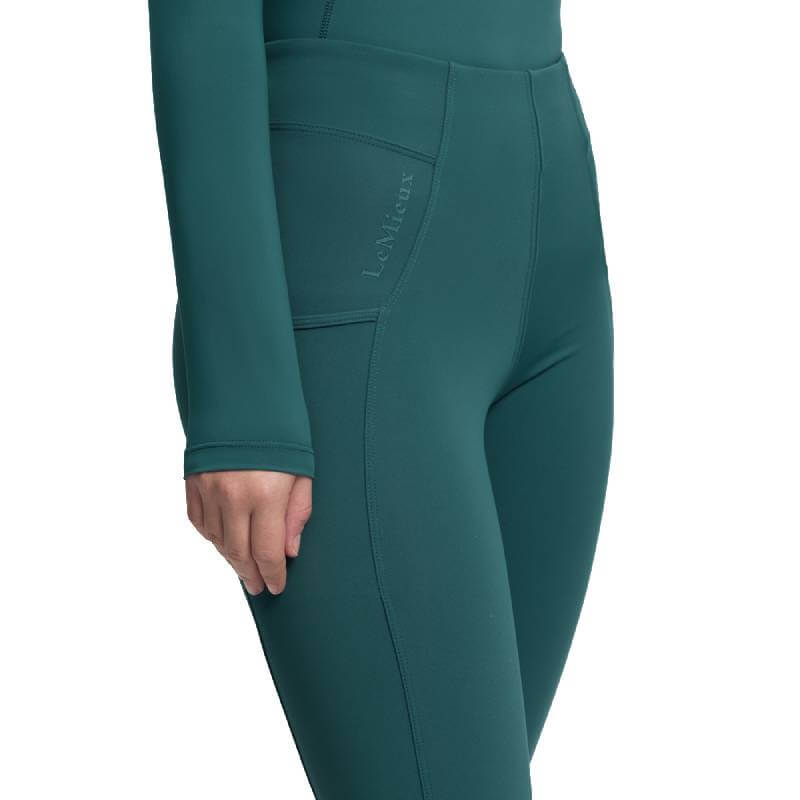 Person in teal LeMieux Young Rider Orla Pull On Breech Jungle, logo on pocket visible.